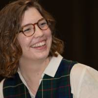 Woman in vest laughs at event table